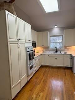 5544 S New Hope Rd, Hermitage, TN 37076 - kitchen featuring a sink, stainless steel appliances, vaulted ceiling, light countertops, and light wood-style flooring
