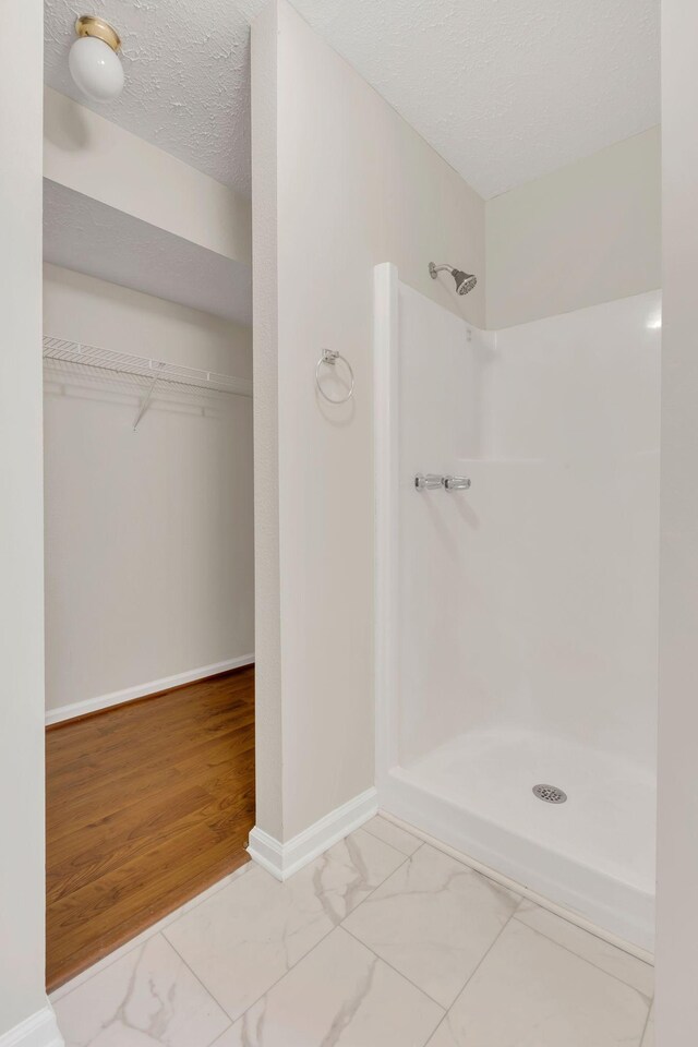 4008 Amber Way, Spring Hill, TN 37174 - full bath with walk in shower, marble look tile flooring, a spacious closet, baseboards, and a textured ceiling