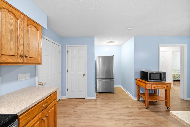 332 Meadowbrook Dr, Cadiz, KY 42211 - kitchen featuring freestanding refrigerator, black microwave, light wood-style flooring, light countertops, and baseboards