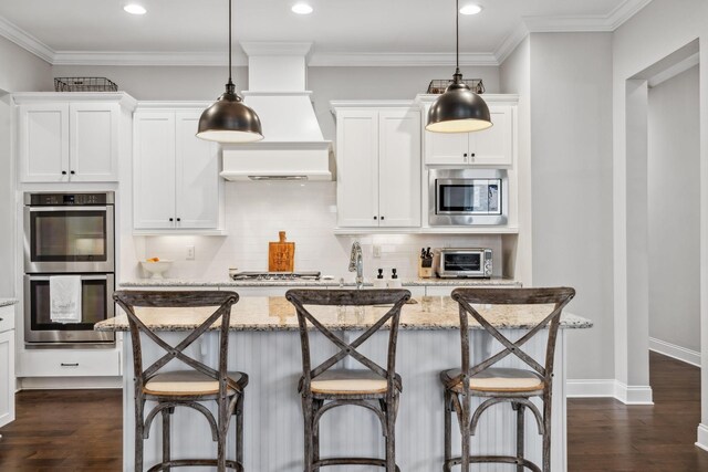 807 Caledonian Ct, Franklin, TN 37064 - kitchen with stainless steel appliances, a kitchen island, dark wood-type flooring, light stone countertops, and ornamental molding