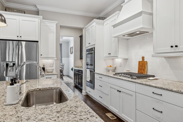 807 Caledonian Ct, Franklin, TN 37064 - kitchen featuring custom exhaust hood, appliances with stainless steel finishes, a sink, white cabinetry, and ornamental molding