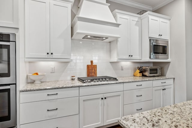 807 Caledonian Ct, Franklin, TN 37064 - kitchen featuring custom range hood, stainless steel appliances, crown molding, tasteful backsplash, and white cabinetry