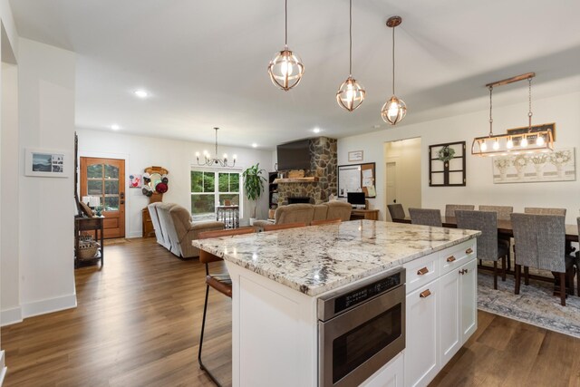 5660 Bold Springs Rd, Mc Ewen, TN 37101 - kitchen featuring stainless steel microwave, dark wood-type flooring, a breakfast bar area, white cabinets, and a chandelier