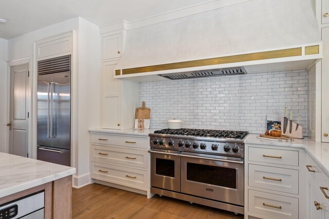 6115 Hillsboro Pike, Nashville, TN 37215 - kitchen featuring high end appliances, light wood finished floors, tasteful backsplash, white cabinets, and light stone countertops