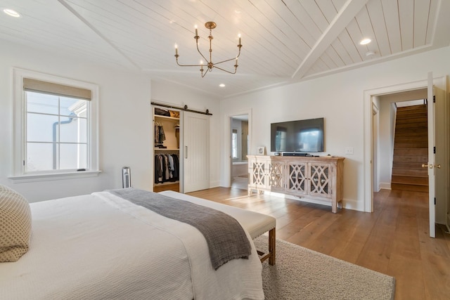 6115 Hillsboro Pike, Nashville, TN 37215 - bedroom with a barn door, a chandelier, a spacious closet, light wood finished floors, and baseboards