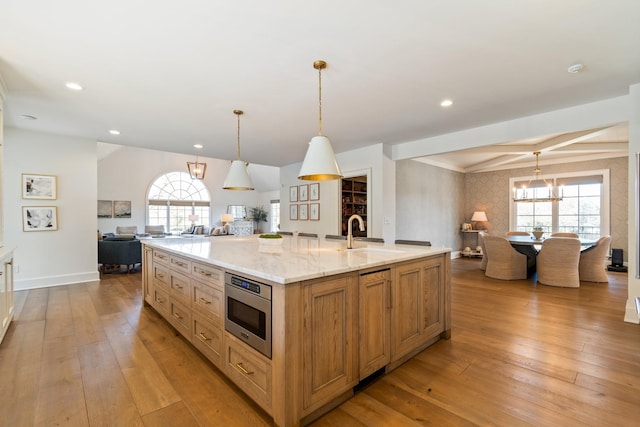 6115 Hillsboro Pike, Nashville, TN 37215 - kitchen featuring open floor plan, a sink, a large island with sink, stainless steel microwave, and light wood-style flooring