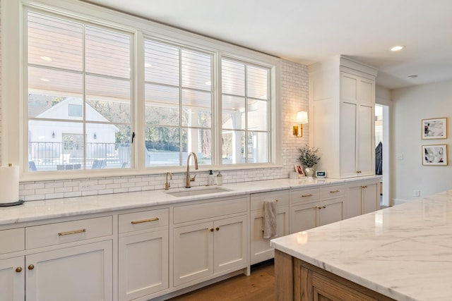 6115 Hillsboro Pike, Nashville, TN 37215 - kitchen featuring a sink, decorative backsplash, light stone countertops, wood finished floors, and white cabinetry
