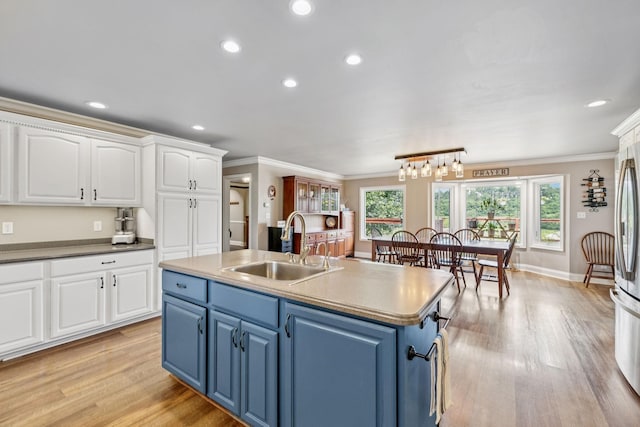 2797 Lewis Rd, Santa Fe, TN 38482 - kitchen with blue cabinets, a sink, white cabinets, crown molding, and light wood-style floors