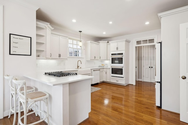 200 Addison Ave, Franklin, TN 37064 - kitchen with white appliances, a peninsula, backsplash, ornamental molding, and light wood-type flooring