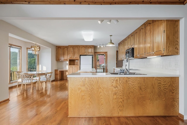 1634 Falling Water Rd, Sparta, TN 38583 - kitchen featuring fridge, a peninsula, black microwave, brown cabinets, and light wood-style floors