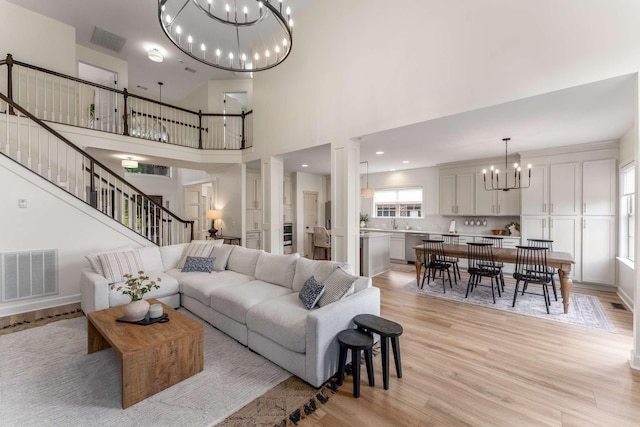 115 Wise Rd, Franklin, TN 37064 - living room featuring a chandelier, light wood-style floors, stairs, a towering ceiling, and ornate columns