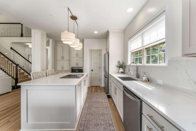 115 Wise Rd, Franklin, TN 37064 - kitchen with appliances with stainless steel finishes, a sink, light wood finished floors, a kitchen island, and pendant lighting