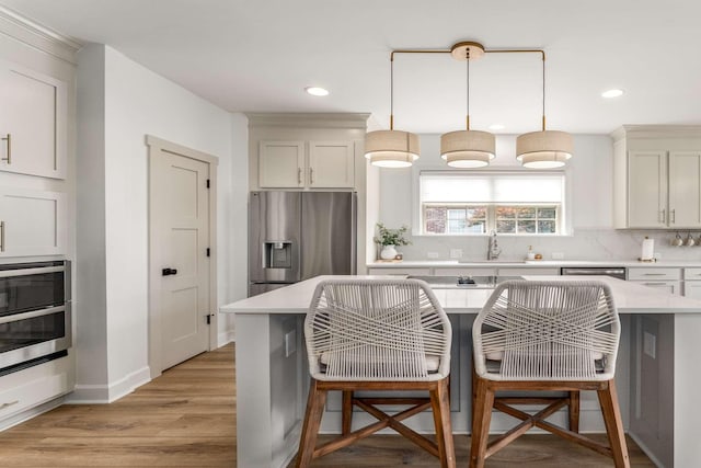 115 Wise Rd, Franklin, TN 37064 - kitchen featuring stainless steel appliances, a breakfast bar, tasteful backsplash, light wood finished floors, and recessed lighting