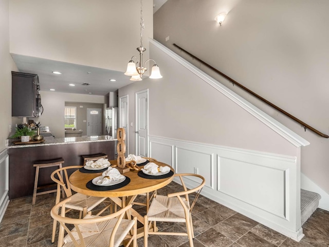 3031 Joseph Dr, Spring Hill, TN 37174 - dining space featuring a wainscoted wall, dark stone finish floors, a chandelier, a decorative wall, and recessed lighting