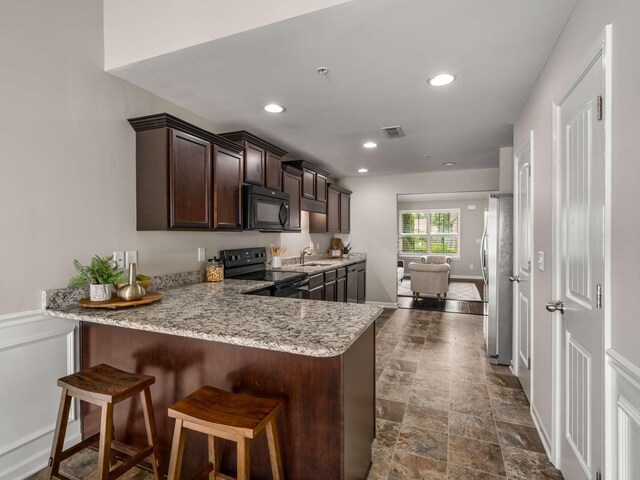 3031 Joseph Dr, Spring Hill, TN 37174 - kitchen with black appliances, a sink, dark brown cabinetry, a peninsula, and light stone countertops