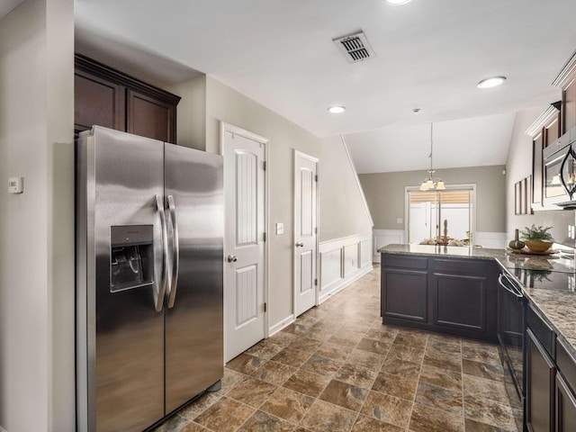 3031 Joseph Dr, Spring Hill, TN 37174 - kitchen with stainless steel appliances, a peninsula, dark brown cabinetry, dark stone finish flooring, and light stone countertops