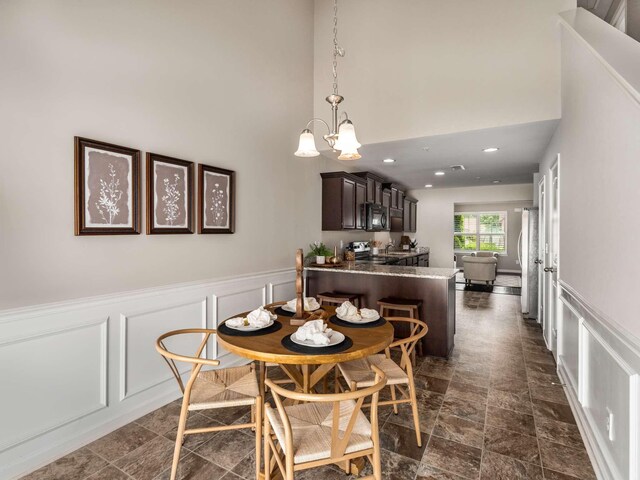 3031 Joseph Dr, Spring Hill, TN 37174 - dining area with a decorative wall, a chandelier, a high ceiling, a wainscoted wall, and dark stone finish floors