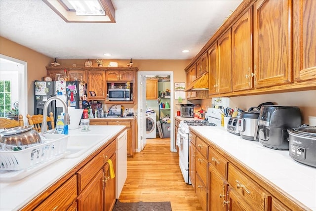 431 Jack Thomas Dr, Manchester, TN 37355 - kitchen with white appliances, washer / dryer, ventilation hood, light wood-style floors, and brown cabinetry