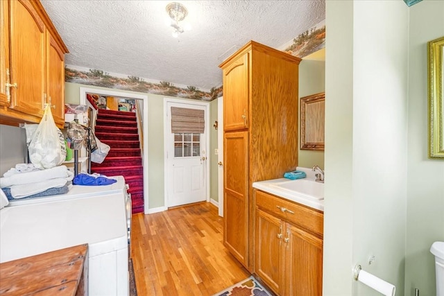 431 Jack Thomas Dr, Manchester, TN 37355 - laundry room with light wood-style floors, a textured ceiling, washer / clothes dryer, and cabinet space