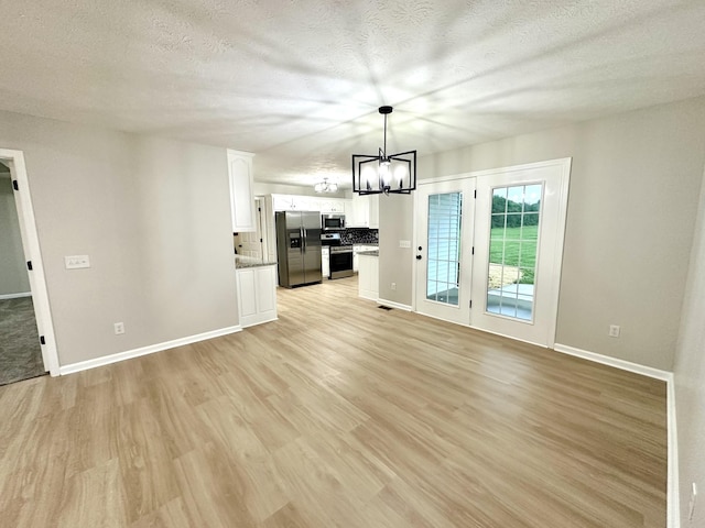 115 Briley Ln, Portland, TN 37148 - unfurnished living room with a chandelier, light wood finished floors, baseboards, and a textured ceiling