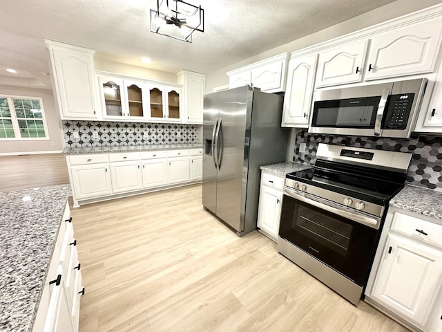 115 Briley Ln, Portland, TN 37148 - kitchen featuring appliances with stainless steel finishes, light wood finished floors, white cabinetry, backsplash, and a textured ceiling