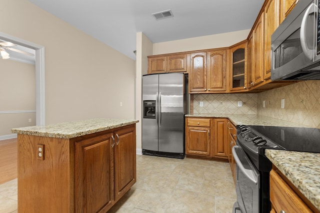 226 Wrennewood Ln, Franklin, TN 37064 - kitchen with stainless steel refrigerator with ice dispenser, range, brown cabinets, and tasteful backsplash