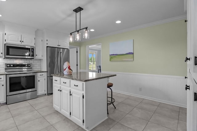 346 Spring Creek Ln, Lebanon, TN 37090 - kitchen with appliances with stainless steel finishes, white cabinetry, dark stone countertops, a wainscoted wall, and ornamental molding