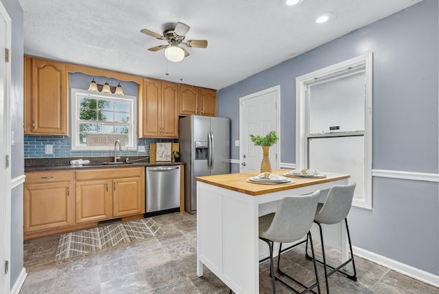 1921 Timberline Cir, Oak Grove, KY 42262 - kitchen featuring appliances with stainless steel finishes, a sink, a ceiling fan, a kitchen breakfast bar, and decorative backsplash