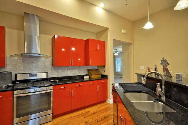 3173 Porter Hills Dr, Clarksville, TN 37043 - kitchen with red cabinetry, stainless steel gas stove, wall chimney exhaust hood, a sink, and light wood-style flooring