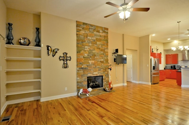 3173 Porter Hills Dr, Clarksville, TN 37043 - unfurnished living room featuring light wood-type flooring, a ceiling fan, a chandelier, a fireplace, and baseboards