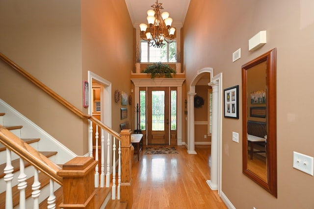 1043 Dorset Dr, Hendersonville, TN 37075 - foyer entrance with arched walkways, ornate columns, a towering ceiling, light wood-style flooring, and a chandelier