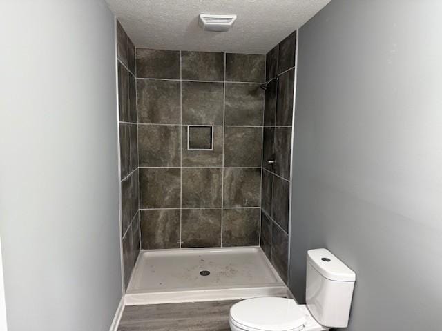 406 New Rock Creek Rd, Tullahoma, TN 37388 - bathroom with toilet, a tile shower, a textured ceiling, and wood finished floors