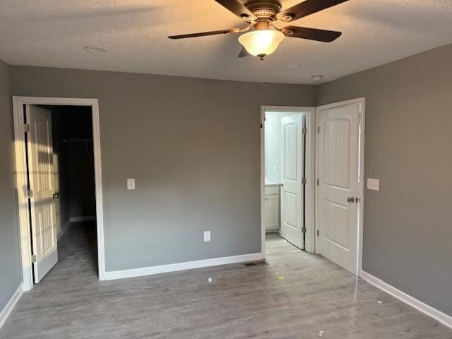 406 New Rock Creek Rd, Tullahoma, TN 37388 - unfurnished bedroom featuring light wood-type flooring, baseboards, a walk in closet, a textured ceiling, and a closet