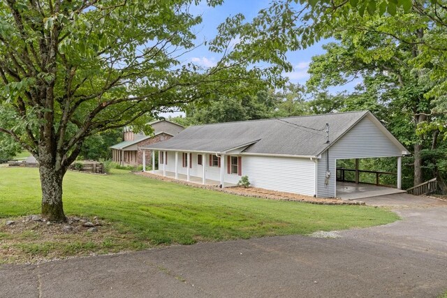 366 Huffman Park Rd, Lynchburg, TN 37352 - view of front of house with covered porch, driveway, a front yard, roof with shingles, and an attached carport