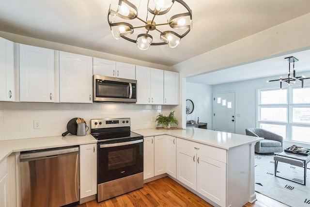 3622 Sabre Dr, Nashville, TN 37211 - kitchen with a chandelier, appliances with stainless steel finishes, light wood finished floors, a peninsula, and backsplash
