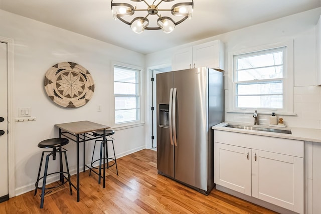 3622 Sabre Dr, Nashville, TN 37211 - kitchen with stainless steel refrigerator with ice dispenser, a sink, a chandelier, white cabinetry, and light wood-type flooring