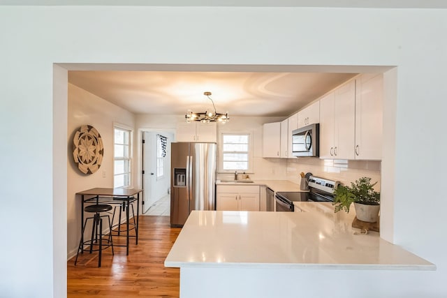 3622 Sabre Dr, Nashville, TN 37211 - kitchen featuring stainless steel appliances, a sink, light wood-style floors, a chandelier, and tasteful backsplash