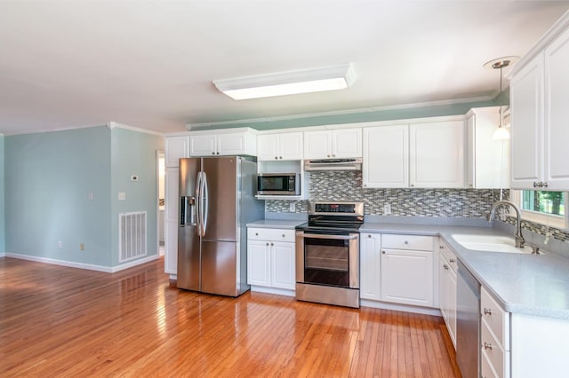 930 Rossview Rd, Clarksville, TN 37043 - kitchen featuring appliances with stainless steel finishes, under cabinet range hood, decorative backsplash, light wood-type flooring, and crown molding
