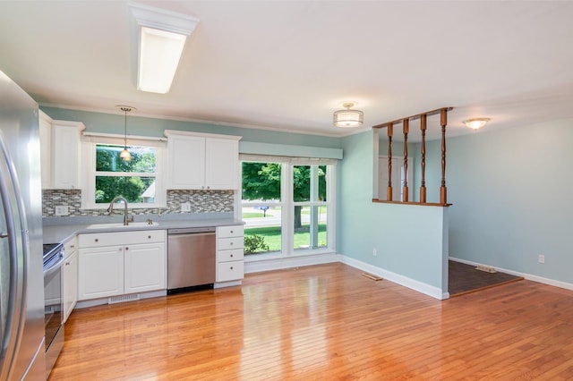 930 Rossview Rd, Clarksville, TN 37043 - kitchen with stainless steel appliances, tasteful backsplash, light countertops, white cabinetry, and light wood finished floors