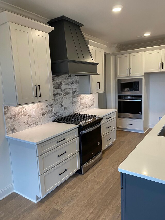 7317 Katherine Ct, Fairview, TN 37062 - kitchen featuring stainless steel appliances, wall chimney exhaust hood, light wood-type flooring, light countertops, and white cabinets