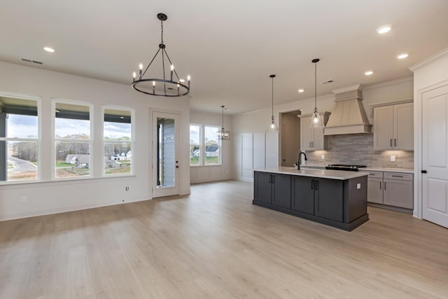 7406 Black Fox Dr, Fairview, TN 37062 - kitchen with a chandelier, premium range hood, light countertops, light wood finished floors, and decorative backsplash