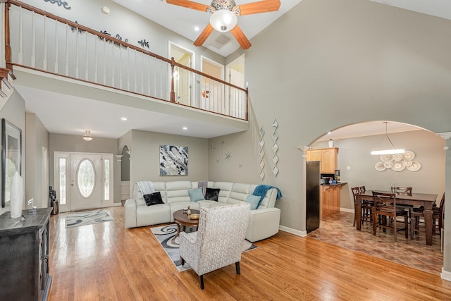 1245 Ben Hill Blvd, Nolensville, TN 37135 - living room with arched walkways, light wood-style floors, a ceiling fan, a towering ceiling, and baseboards