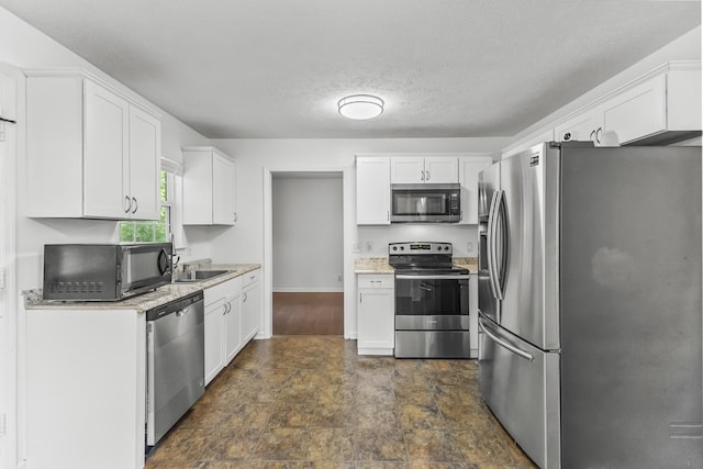 929 Chaparral Dr, Lebanon, TN 37087 - kitchen featuring stainless steel appliances, white cabinets, stone finish floors, a sink, and a textured ceiling