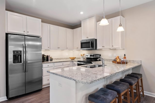 105 Primrose Ln, Gallatin, TN 37066 - kitchen featuring appliances with stainless steel finishes, a sink, dark wood-style flooring, a peninsula, and white cabinetry