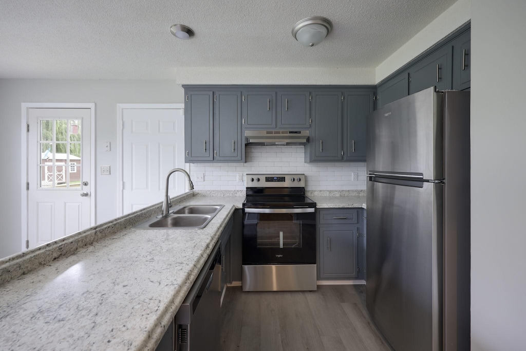 615 Doane Dr, Clarksville, TN 37042 - kitchen featuring appliances with stainless steel finishes, a sink, under cabinet range hood, wood finished floors, and backsplash
