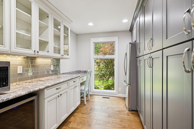 8226 Frontier Ln, Brentwood, TN 37027 - indoor dry bar with appliances with stainless steel finishes, beverage cooler, light wood-type flooring, decorative backsplash, and recessed lighting