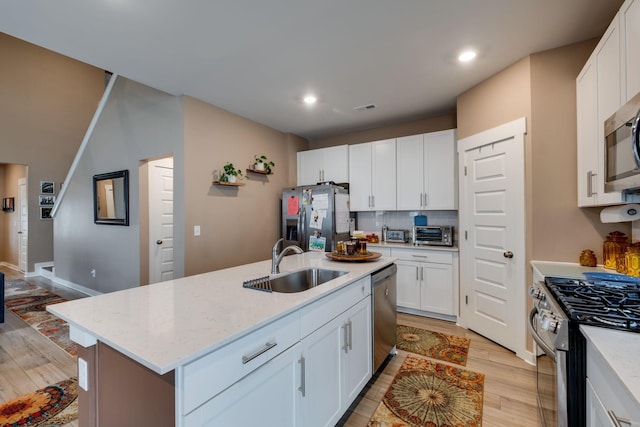 1605 Medinah Ln, Lebanon, TN 37087 - kitchen featuring appliances with stainless steel finishes, light wood-type flooring, white cabinetry, a center island with sink, and backsplash
