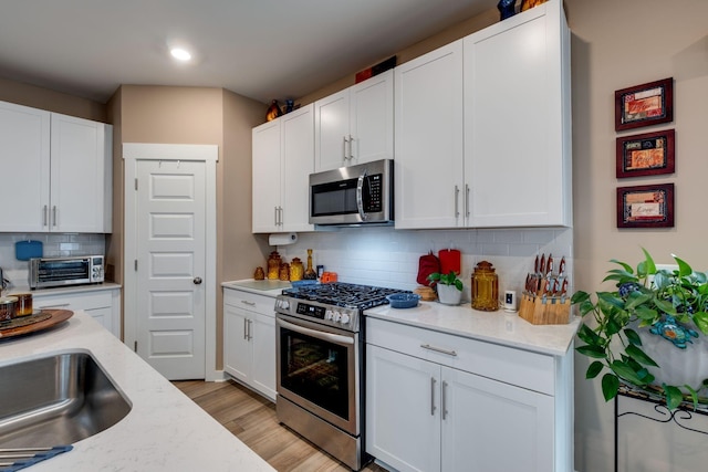 1605 Medinah Ln, Lebanon, TN 37087 - kitchen with stainless steel appliances, tasteful backsplash, white cabinetry, light wood-type flooring, and recessed lighting