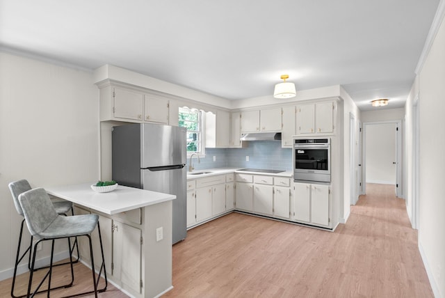 415 Jordan Rd, Clarksville, TN 37042 - kitchen with stainless steel appliances, under cabinet range hood, a peninsula, backsplash, and light wood-type flooring