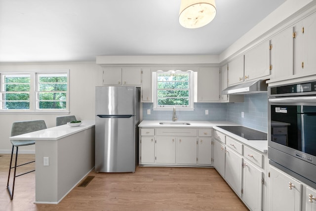 415 Jordan Rd, Clarksville, TN 37042 - kitchen featuring appliances with stainless steel finishes, under cabinet range hood, light countertops, backsplash, and light wood-type flooring